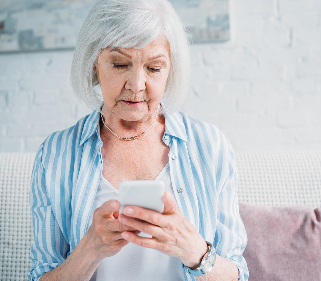 portrait of senior woman using smartphone while resting on couch