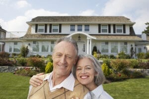 Mature couple arm in arm outside house, smiling, portrait