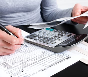 Person doing their taxes with a calculator and pen