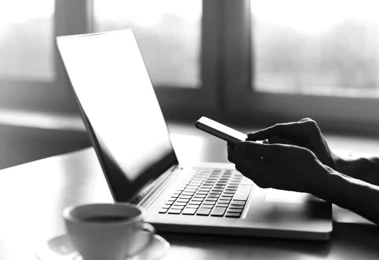 Male hands using smart phone and laptop computer