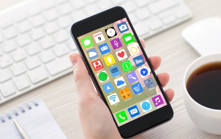 woman hands holding coffee white phone with home screen icons apps and keyboard