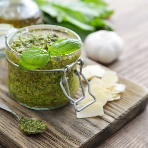 Fresh made Pesto Sauce in glass jar on wooden background