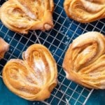 Homemade sugar buns on a cooling rack with sugar for sprinkling. Palmiers, elephant ear, puff pastry cookie.