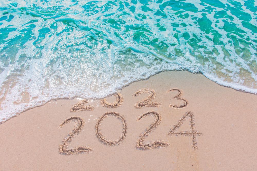 Message Year 2023 replaced by 2024 written on beach sand background